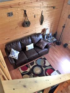 un canapé en cuir dans une pièce avec un mur en bois dans l'établissement Secluded Cabin on Organic Working Farm in the Ozarks of Northern Arkansas, à Maumee