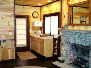 a kitchen with a fireplace and a clock on the wall at Romantic Ozarks Cabin Rental in Secluded Woodland near Branson, Missouri in Hollister