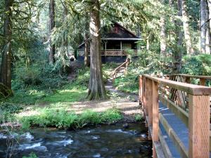 a bridge over a stream in front of a cabin at Secluded Forest Cabin in Rhododendron near Mt Hood Village in Oregon in Brightwood