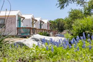 a row of wooden houses with flowers in the foreground at Fabulous Cozy Airstream Perfect for a Small Family Unique Escape in Texas in Spicewood