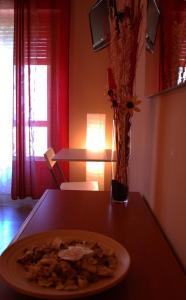 ein Teller mit Essen auf einem Tisch mit einer Vase Blumen in der Unterkunft Un Letto a Casteddu in Cagliari