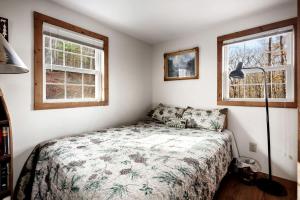 a bedroom with a bed and two windows at Lustrous Lakefront Cabin Oasis near Lake Ferndale in West Virginia in Springfield