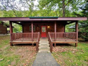 a log cabin with two benches and a red door at Charming Riverside Cabin Sanctuary Near New River, Virginia in Galax