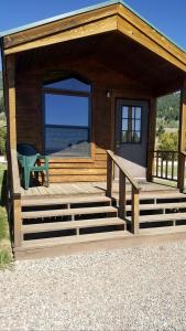 a small cabin with a large window and a porch at Impressive Cabin with Gorgeous Lake Vistas near West Yellowstone, Montana in Lakeview