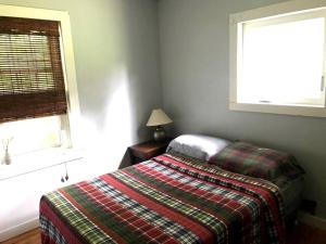 1 dormitorio con 1 cama con manta a cuadros y ventana en Superb Family Cabin with Mountain Views and Deck in Shandaken, New York, en Shandaken