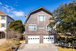 a brick house with two white garage doors at Gorgeous Waterfront Vacation Rental for an Unforgettable Family Getaway in Frisco, North Carolina in Frisco
