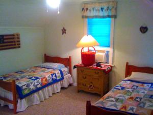a bedroom with two beds and a lamp on a dresser at Historic Vacation Rental on Acres of Farmland near Aloha State Park, Michigan in Alverno +19 photos