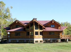 une grande maison en bois avec un toit rouge dans l'établissement Delightful Cabin Rental near Custer Gallatin National Forest, Montana, à Absarokee