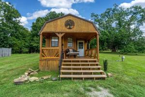 a small wooden cabin with stairs in a field at Serene Loft Cabin with Outdoor Grill and Fire Pit in Creal Springs, Illinois in Sunset Harbor