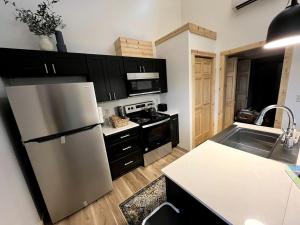 a kitchen with a stainless steel refrigerator and black cabinets at Cozy Rustic Cabin with Hot-Tub Ideal for a Couples Retreat in Illinois in Etherton