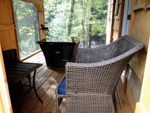 a porch with two wicker chairs and a table at Romantic Cabin Rental Overlooking Otter Creek in the Adirondacks of Upstate New York in Greig +5 photos