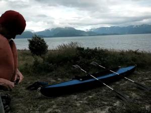 a man standing next to a kayak next to the water at Luxury Camping Tent Overlooking Kachemak Bay in Homer, Alaska in Fritz Creek