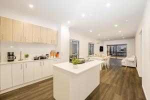 a kitchen with white cabinets and a living room at 3 Bedroom 3 Bath Accessible Bathrooms in Melton South