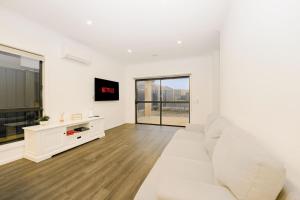 a white living room with a white couch and a tv at 3 Bedroom 3 Bath Accessible Bathrooms in Melton South