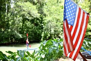 eine Frau auf einem Surfbrett neben einer amerikanischen Flagge in der Unterkunft Friendship by the Water: Texas Tented Cabin Oasis for a Lakeside Getaway in Marion