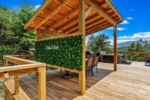 a wooden deck with a pergola and a table and chairs at Modern A-Frame Cabin with Breathtaking Views of the Smoky Mountains, Perfect for Families or Groups in Hartford