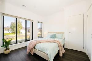 a white bedroom with a bed and a large window at 3 Bedroom 3 Bath Accessible Bathrooms in Melton South