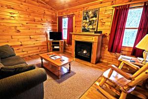 a living room with a fireplace in a log cabin at Cozy Log Cabin near Hocking Hills State Park, Ohio in Cedar Grove