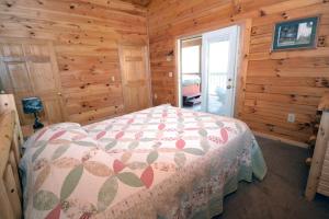 a bedroom with a bed in a wooden cabin at Cozy Log Cabin near Hocking Hills State Park, Ohio in Cedar Grove