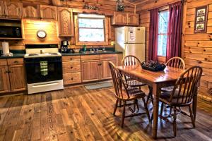a kitchen with a table and chairs and a refrigerator at Cozy Log Cabin near Hocking Hills State Park, Ohio in Cedar Grove +10 photos