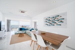 a living room with a wooden table and white chairs at Brisa Da Ria Apartment, Formosa Village in Fuzeta