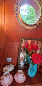 a table with a mirror and a vase with red roses at Chez Gabrielle - Cabine du marinier Luxe Péniche AINOS LOUANGES cadre exceptionnel in Auxerre +3 photos