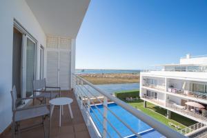 a balcony with a table and a view of the ocean at Brisa Da Ria Apartment, Formosa Village in Fuzeta
