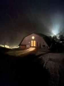 Un granero de noche con una luz encendida en Impressive Barn Suite with Hot-tub and Petting Zoo in Sugar Grove, North Carolina, en Forest Grove