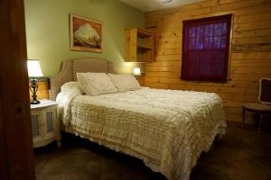 a bedroom with a bed with a white bedspread and a window at Spacious Log Cabin Rental for Family Vacations in Texas in Nacogdoches +28 photos