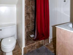 a bathroom with a toilet and a red shower curtain at Spacious Log Cabin Rental for Family Vacations in Texas in Nacogdoches +28 photos