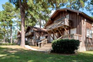 a large wooden house with stairs and a tree at Spacious Log Cabin Rental for Family Vacations in Texas in Nacogdoches
