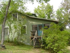 une petite maison verte avec un porche et une échelle dans l'établissement Charming Cabin Rental on Lake Paradox for Group Getaway in Adirondacks, New York, à Severance
