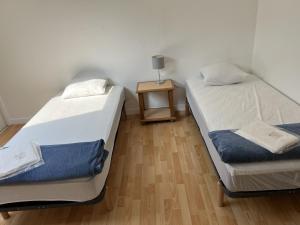 two beds in a room with a side table at Hébergements le Camp d'Auneau - Aunay Bien in Auneau