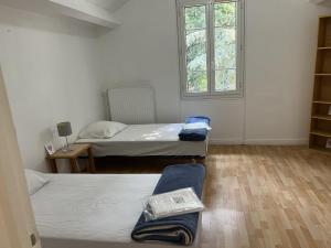 a small room with two beds and a window at Hébergements le Camp d'Auneau - Aunay Bien in Auneau +2 photos