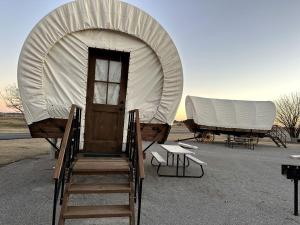 una grande tenda bianca, alcune sedie e un tavolo di Perfect Glamping Vacations in this Rustic Conestoga Covered Wagon Rental in Oklahoma a Moore