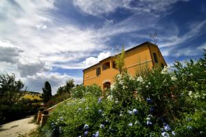 un edificio amarillo en la cima de una colina con flores en Villa Scuderi, en Recanati