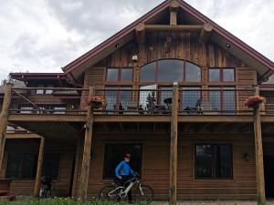 a man riding a bike in front of a house at Family-Friendly Cabin Rental with Lone Peak Views in Big Sky in Big Sky Mountain Village