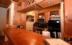 a kitchen with a wooden table and a black refrigerator at Family-Friendly Cabin Rental with Lone Peak Views in Big Sky in Big Sky Mountain Village +31 photos