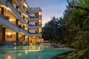 a hotel with a swimming pool at night at Anumana De Suite in Ubud