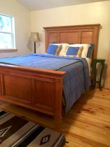 une chambre avec un grand lit en bois avec des draps bleus dans l'établissement Forested Wood Cabin near Ocala National Forest in Central Florida, à Fort McCoy