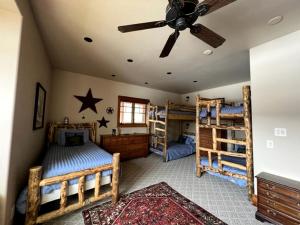 a bedroom with two bunk beds and a ceiling fan at Scenic Creekside Lodge with Decks and Madison River Access near Yellowstone, Ennis Montana in Grahams Place