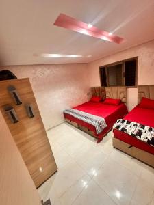 a bedroom with two beds with red sheets at Belle maison avec piscine à 7 min de la plage en voiture in Dar Bouazza +60 photos