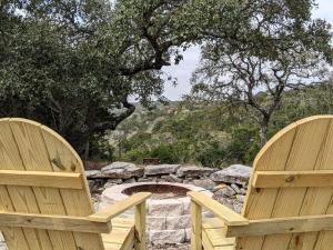 two wooden chairs sitting in front of a fire pit at Tiny House with Amazing Views and Private Hiking Trails in Hill Country, Texas in Freedom Springs Ranch Airport