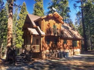 a log cabin with a balcony in the woods at Family-Friendly Log Cabin Rental in California's Gold Country near Sacramento in Barton