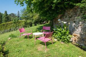 due sedie rosa e un tavolo nell'erba di Le Pressoir - Newly refurbished house with contemporary decoration a Saint-Cyr-au-Mont-dʼOr