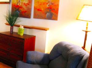 a living room with a chair and a dresser with a lamp at Stately 20-Person Beach Vacation Rental on the Shores of Lake Michigan near Muskegon, Michigan in Montague