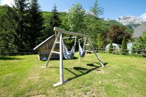 a swing set in a yard with a house at Cozy Cabin in Triglav National Park for Family Getaways in Slovenia in Soča +7 photos