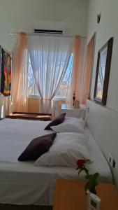 Un dormitorio con dos camas blancas y una ventana. en Branco Por do sol próximo aeroporto, en Porto Alegre