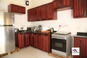 Una cocina con gabinetes de madera y un horno de estufa. en Villa Grace - Namugongo Road, en Kampala