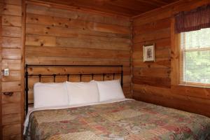 a bedroom with a bed in a log cabin at Charming Cabin Rental in the Forest near Beckley, West Virginia in Hico